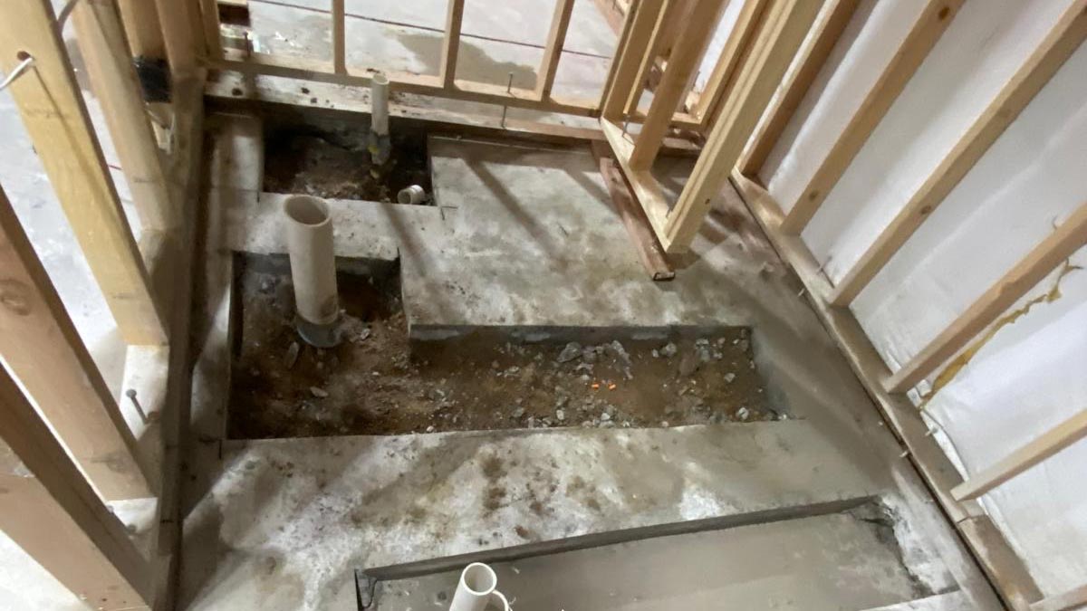 New basement bathroom framing with plumbing rough-in lines run through open stud walls