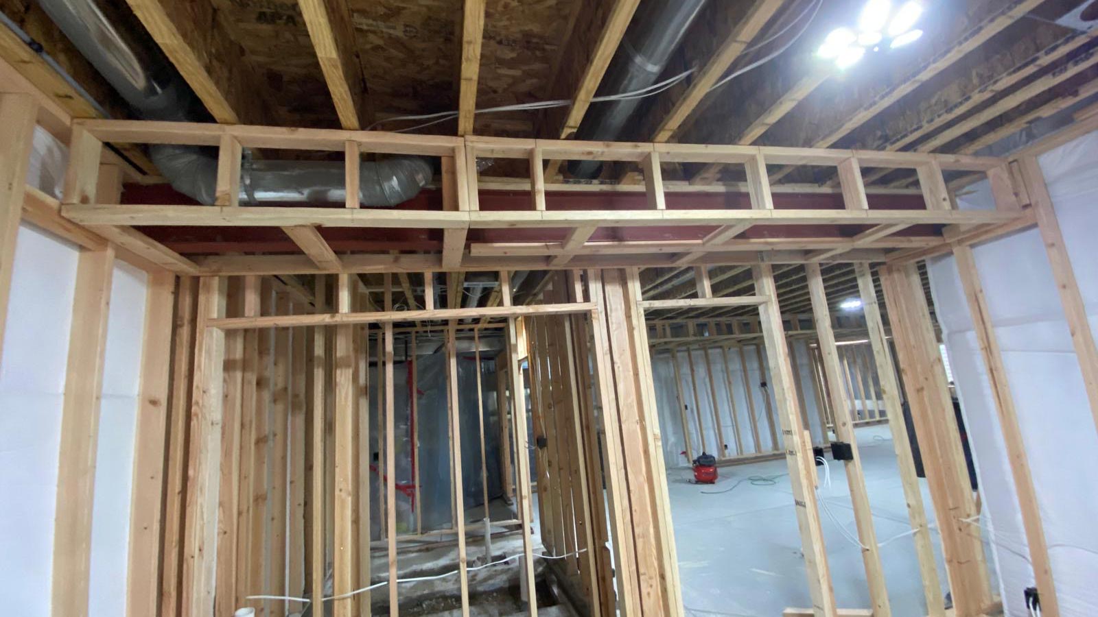 Basement framing with HVAC ductwork boxed into a tight soffit to preserve ceiling height