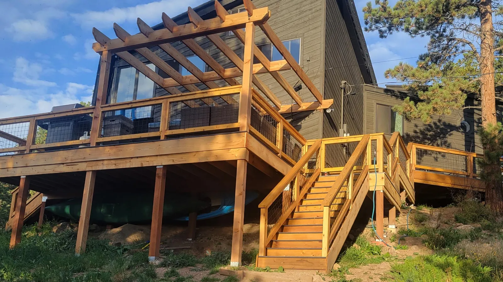 New cedar deck with a pergola overhead and wide wooden stairs down to the yard