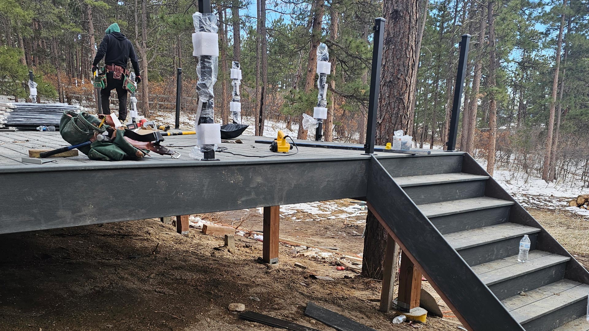 Deck framing with composite stairs under construction — footing and framing inspections vary by Denver-metro city