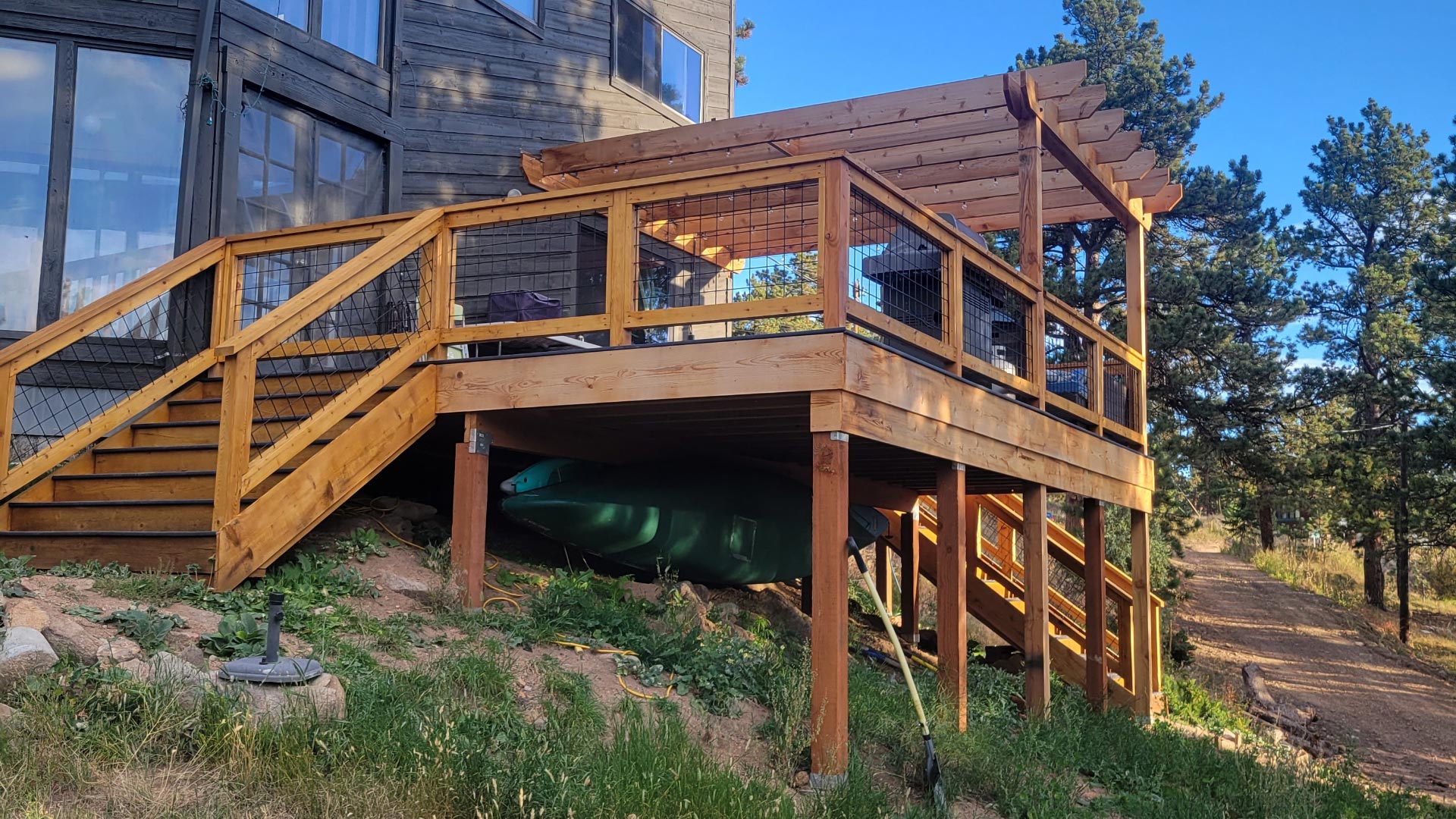 Side view of an elevated wood deck with pergola posts and beams above