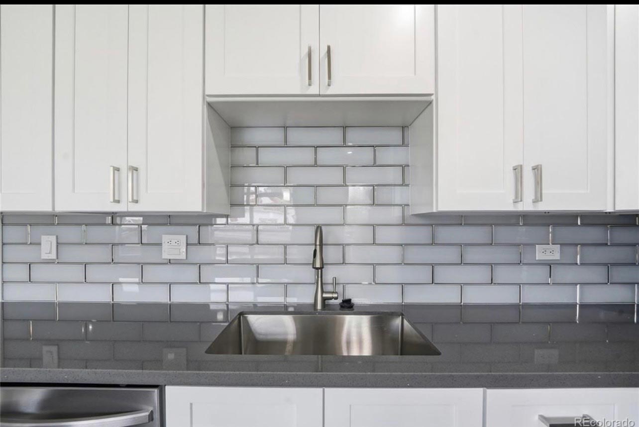 Close-up of a gray subway tile kitchen backsplash above an undermount sink with modern faucet
