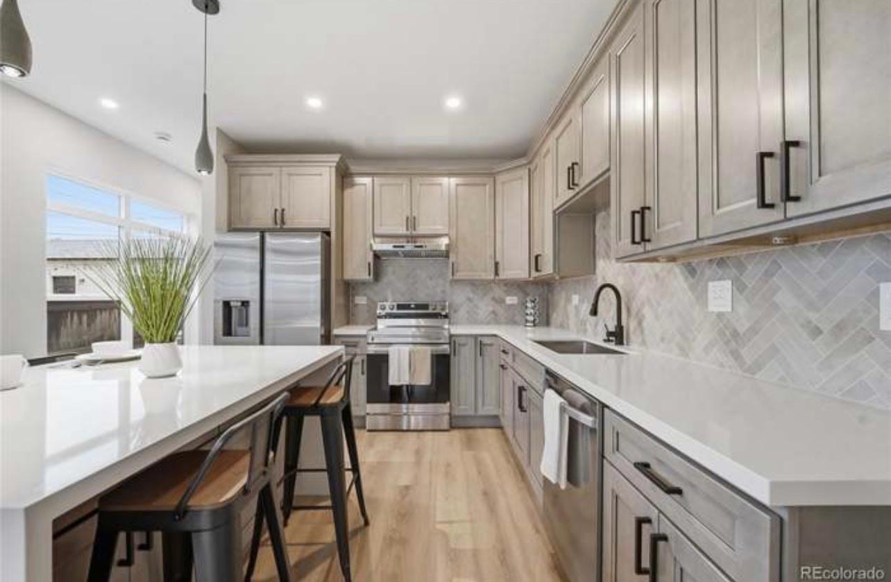 Remodeled kitchen with gray shaker cabinets and a white herringbone tile backsplash