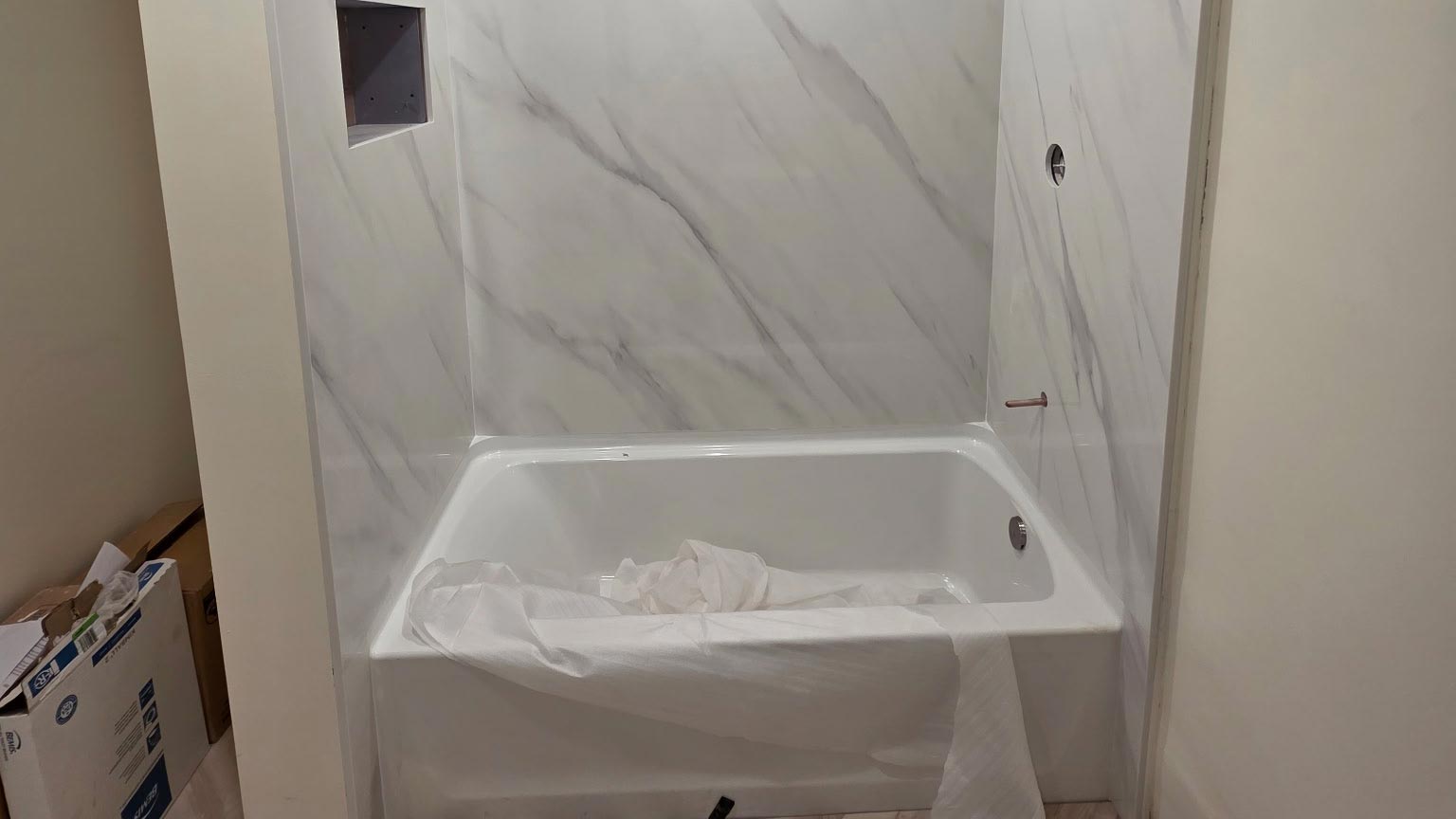 Tub-to-shower conversion in progress with marble-look wall panels installed in the alcove