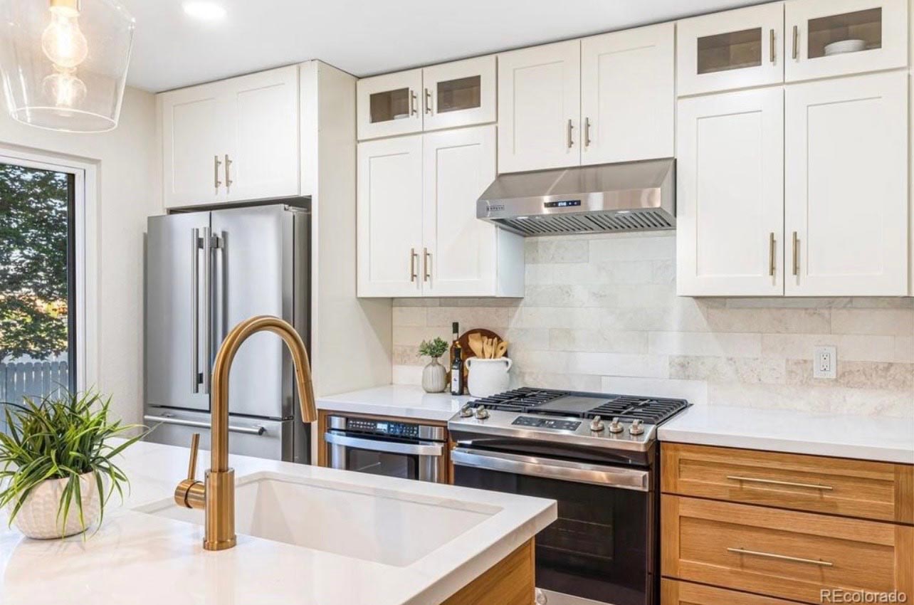 Two-tone kitchen with white upper cabinets, wood-tone lowers and a stainless gas range