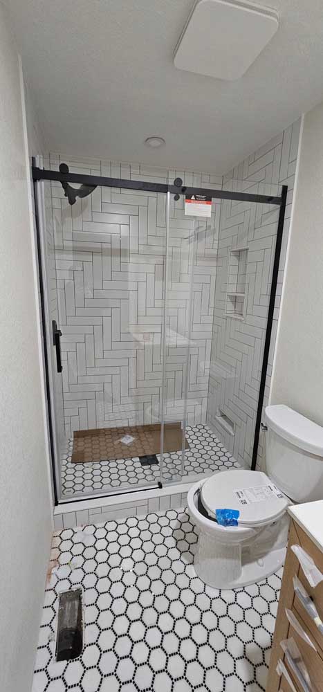 Walk in shower white herringbone tile hexagon floor — bathroom remodel by BH Builders, Denver metro