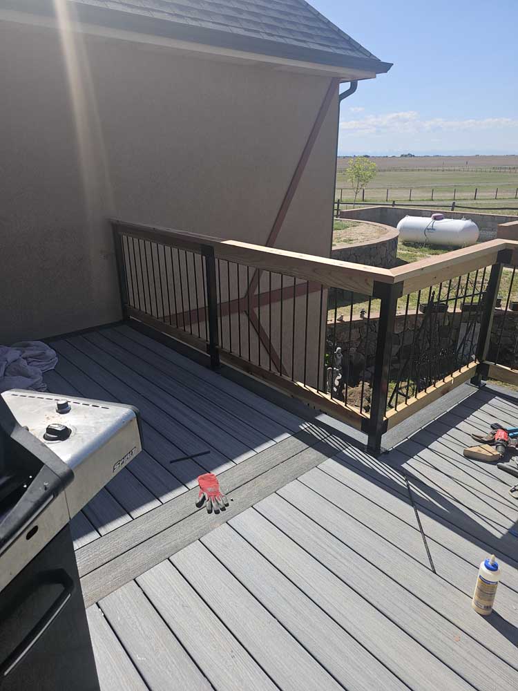 Finished gray composite residential deck with dark metal baluster railing and clean perimeter detailing