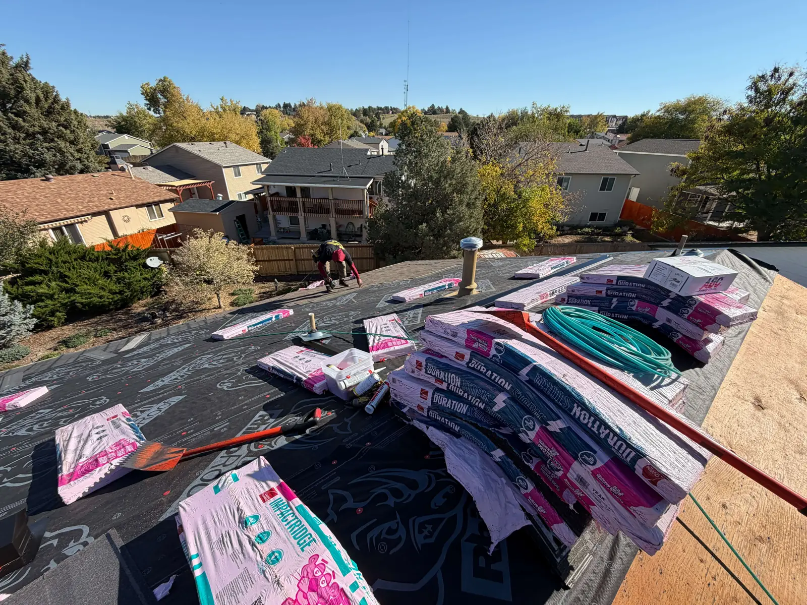 Owens Corning Duration STORM shingle bundles labeled Teak on black RhinoRoof underlayment.