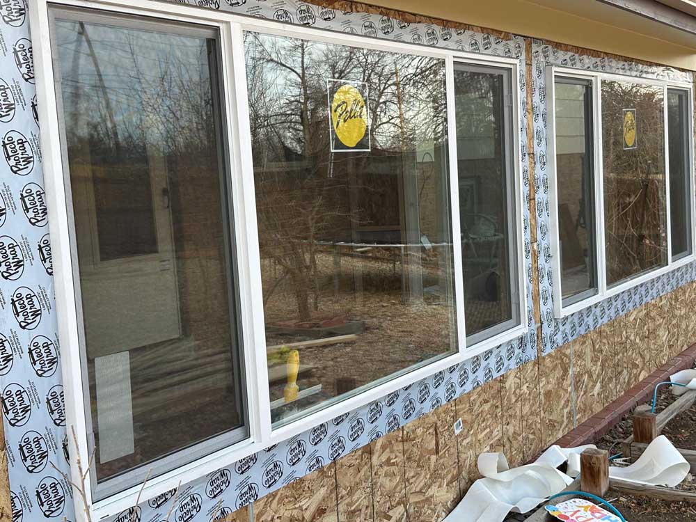 New residential windows installed into sheathing with flashing tape and weather barrier exposed
