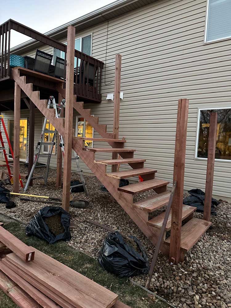 Wood deck stairs completed tan vinyl siding — exterior remodel by BH Builders, Denver metro