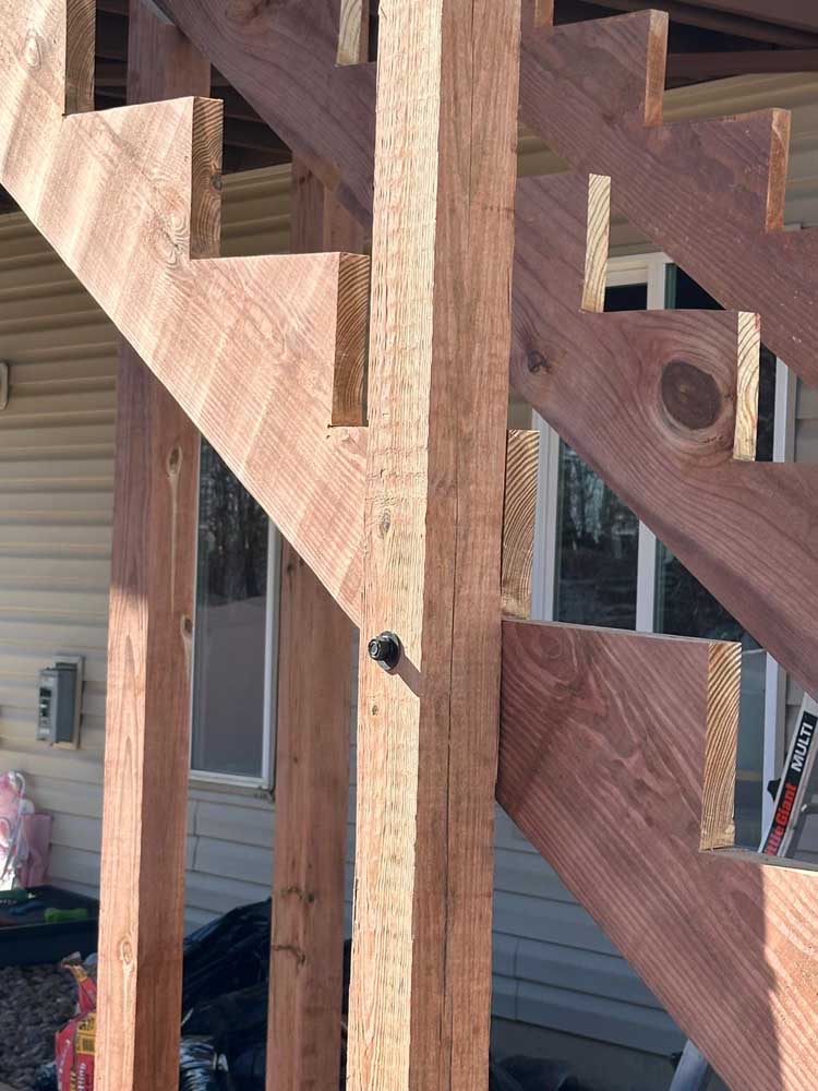 Close-up of a deck stair stringer through-bolted to its support post