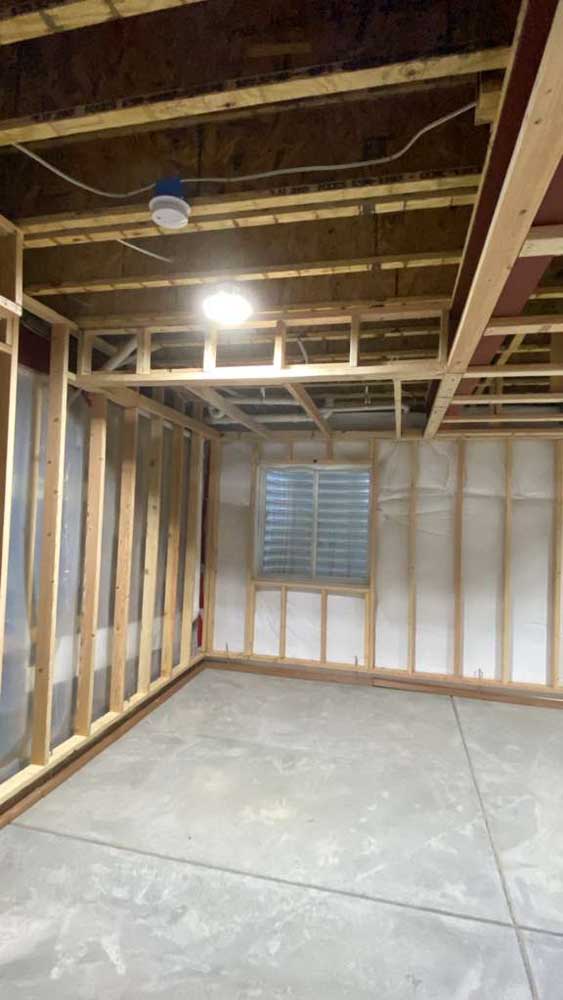 Basement wall framing around a window beneath exposed ceiling joists before rough inspections