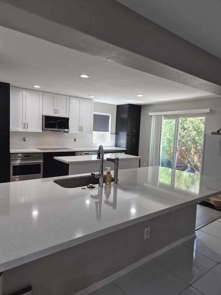 Open-layout kitchen with white quartz island after a wall removal, from a BH Builders Denver-metro remodel