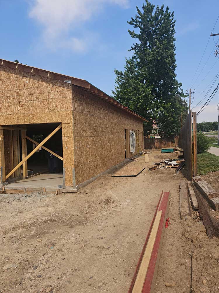 Side view of a detached garage under construction with wall framing and sheathing complete