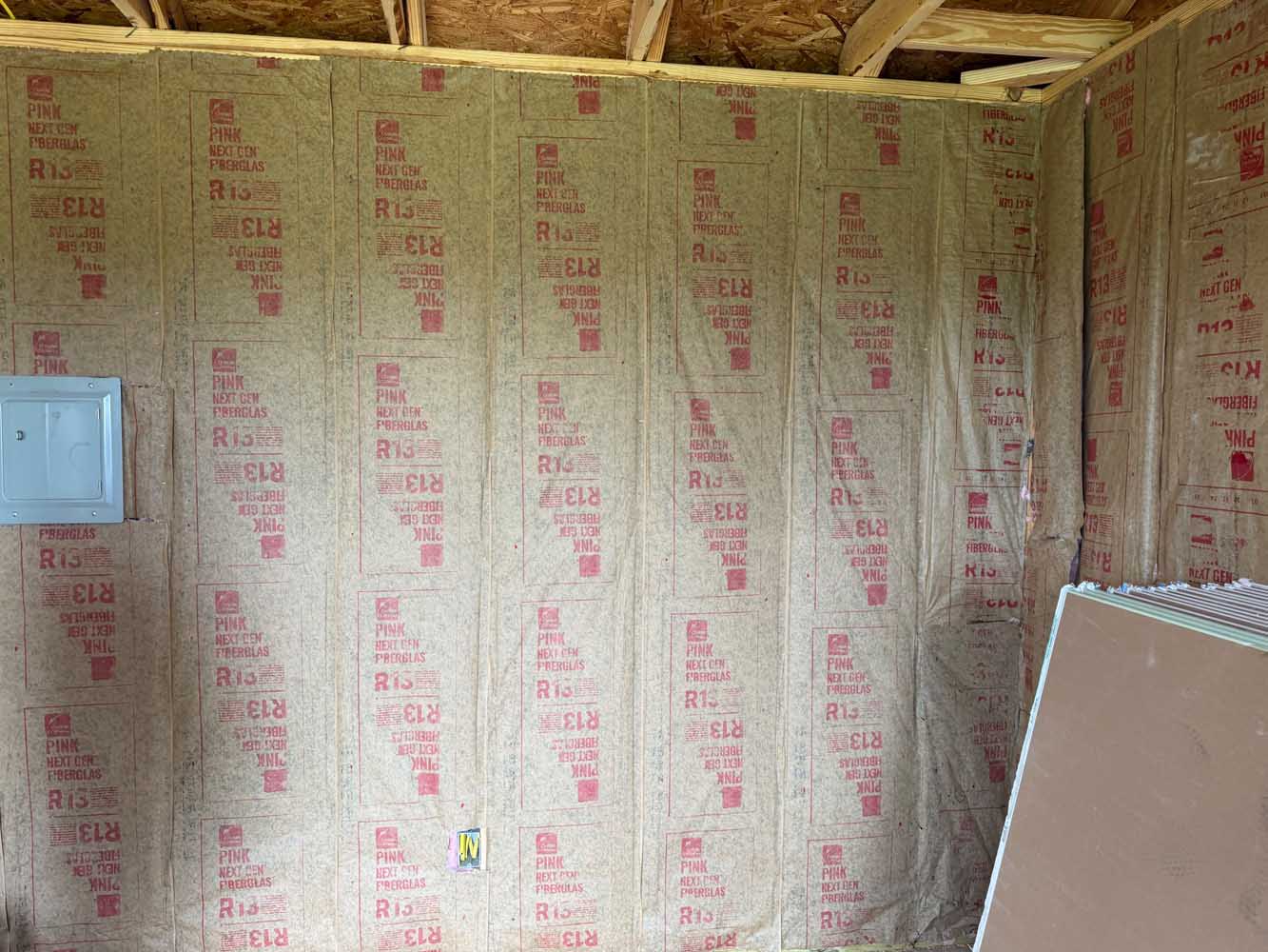 Wall insulation installed between studs before drywall — the insulation inspection required by tightening energy codes