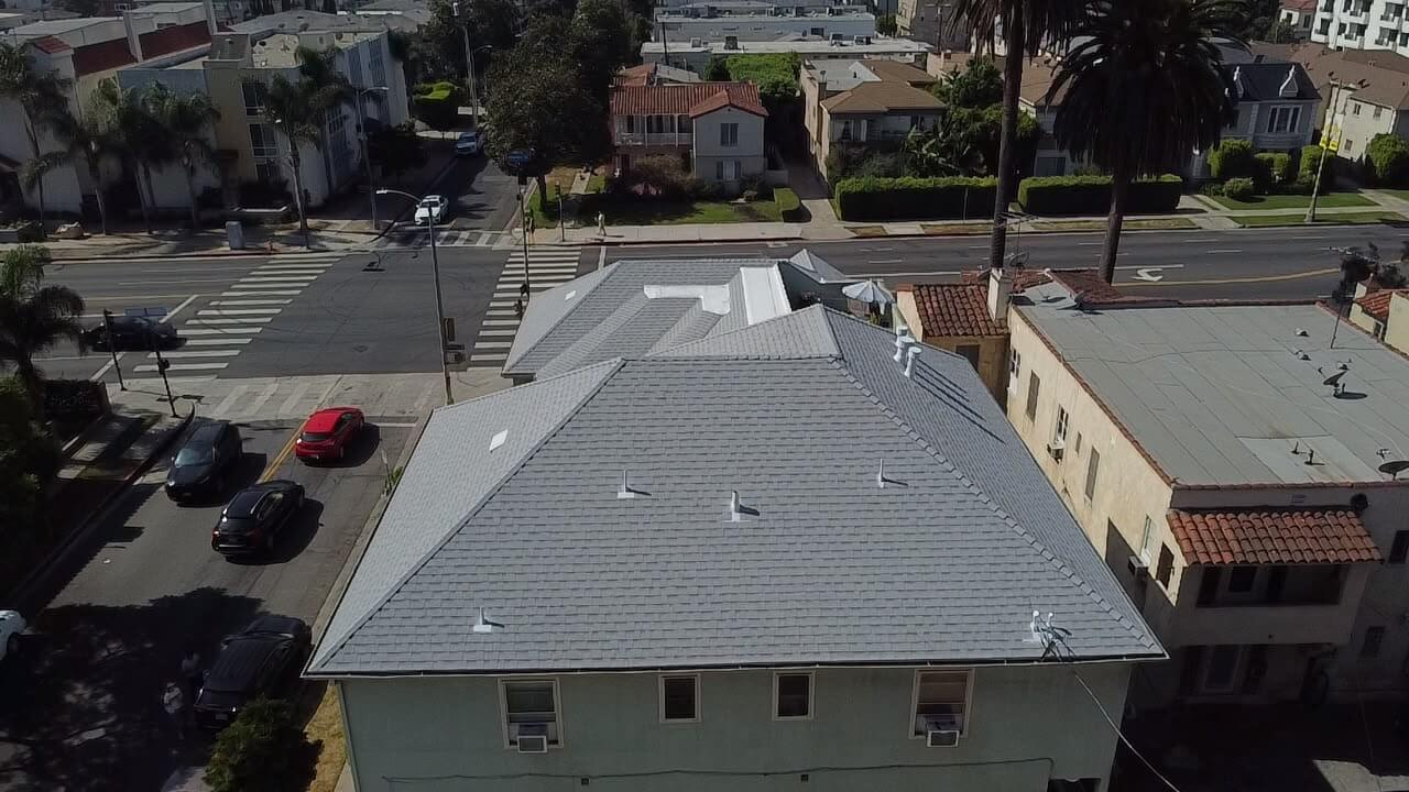 Aerial view of a completed asphalt shingle replacement on a large hip roof