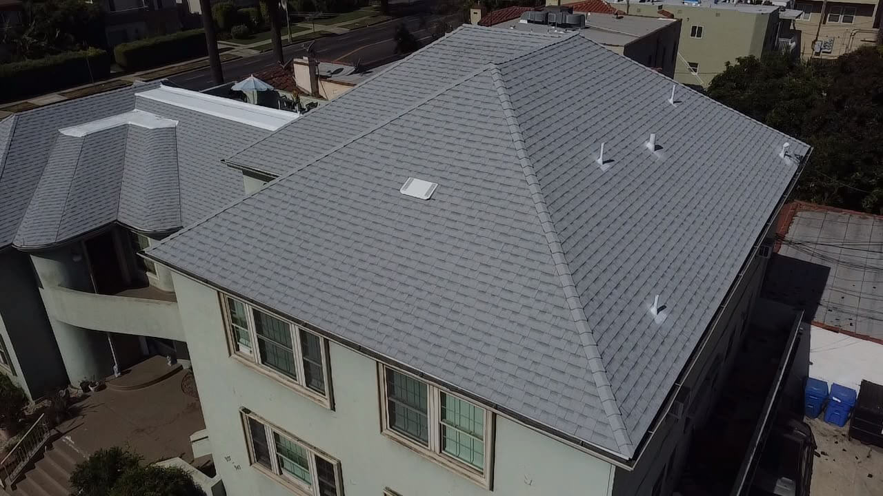 New architectural asphalt shingle hip roof from above with fresh vents and skylight