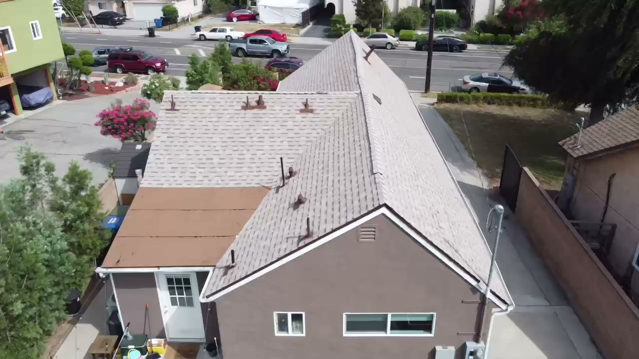 Drone view of an asphalt shingle roof replacement in progress, new decking down and architectural shingles going on