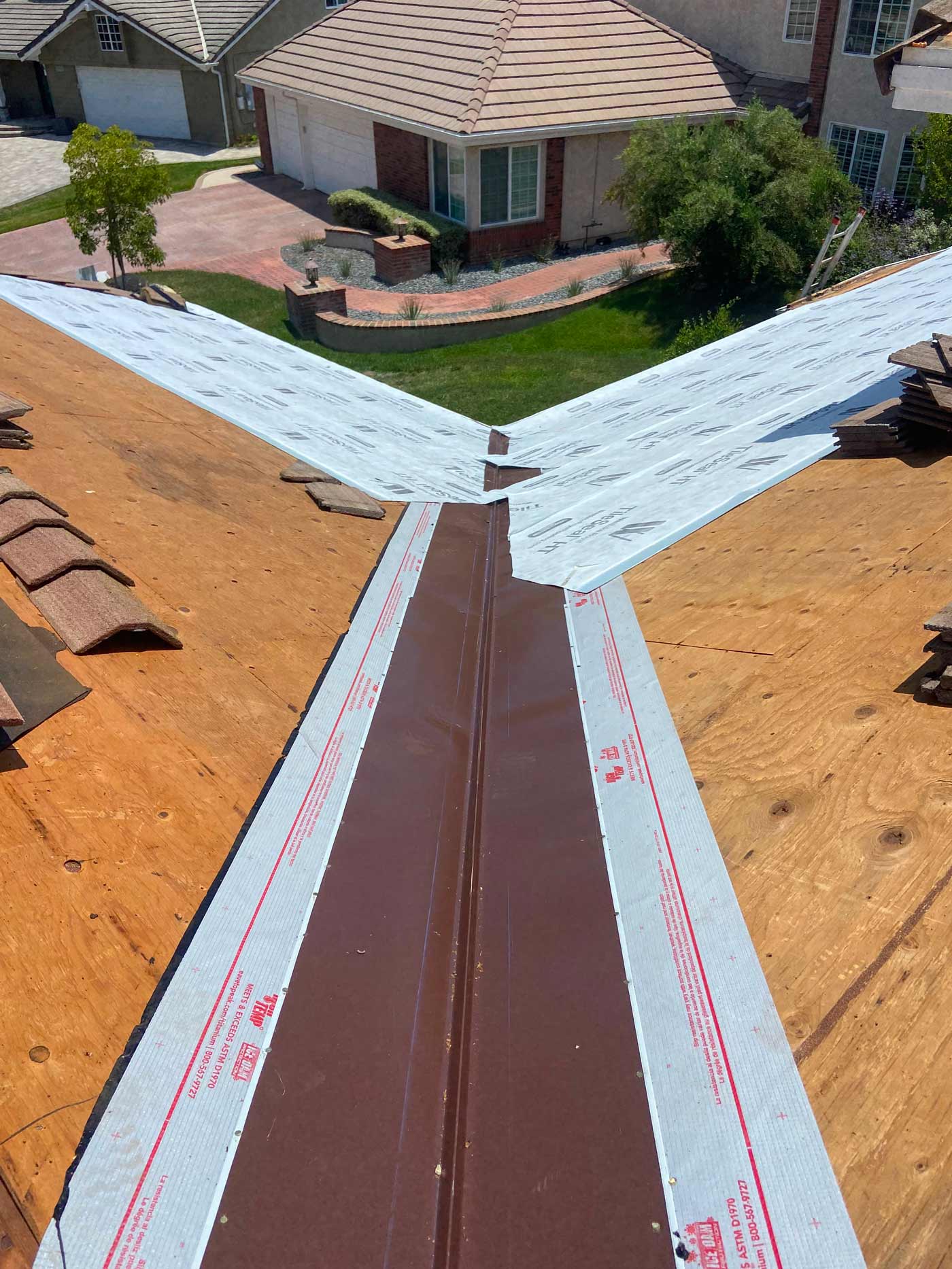 Close-up of new brown ridge metal with ice and water shield membrane over plywood roof decking