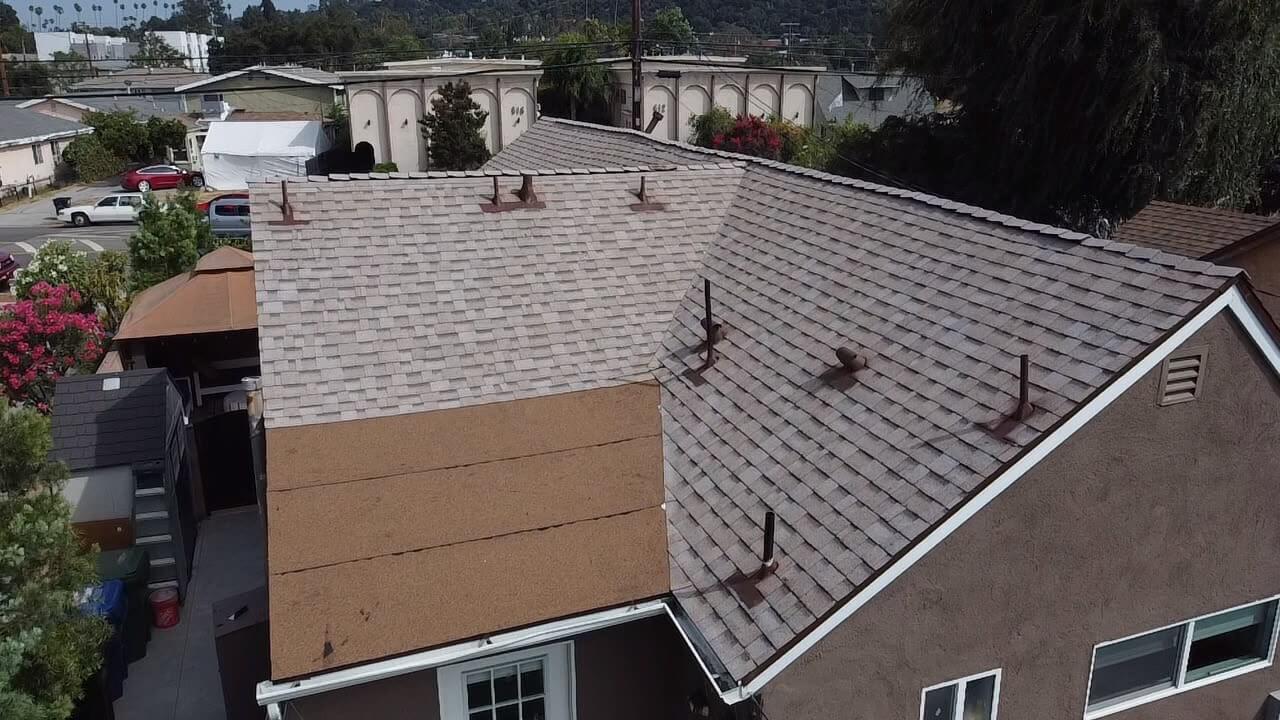 Shingle re-roof in progress showing new decking panels and shingles advancing across the slope