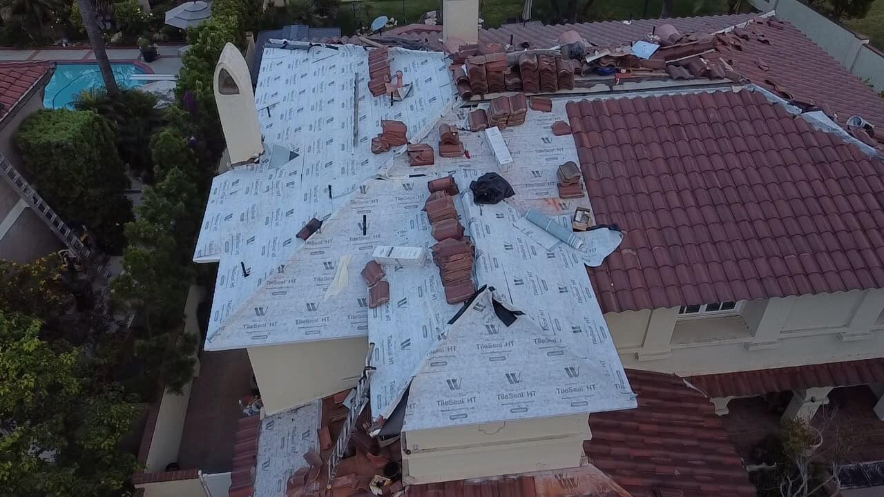 Tile roof replacement in progress with high-temp underlayment installed and tiles staged for relay